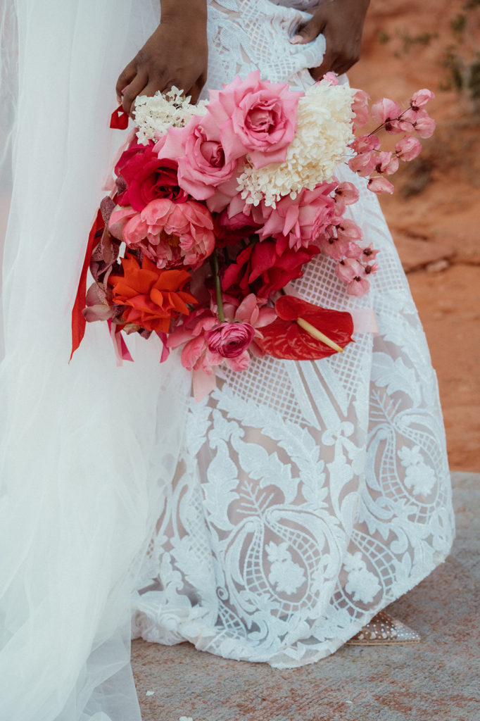 Bold & Colorful in the Vegas Desert. The bride holding her lush monochromatic wild magenta wedding bouquet next to her 