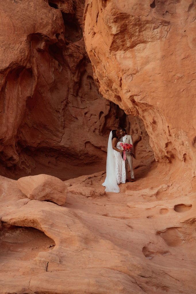 Bold & Colorful in the Vegas Desert. Newlyweds kiss in the middle of the opening in between the rocks of valley of fire 
