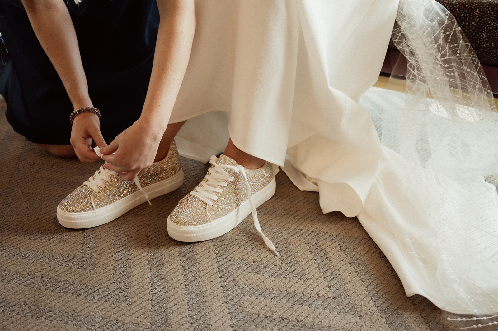 Bride getting her Sparkly Tennis Shoes Tied while Getting Ready 