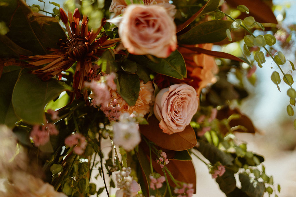 Ceremony florals with blush, salmon, deep red florals  