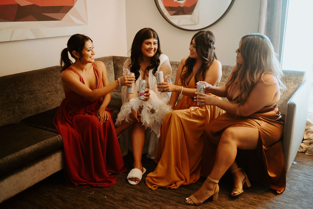 Bridesmaids having a drink together with the bride while getting ready 
