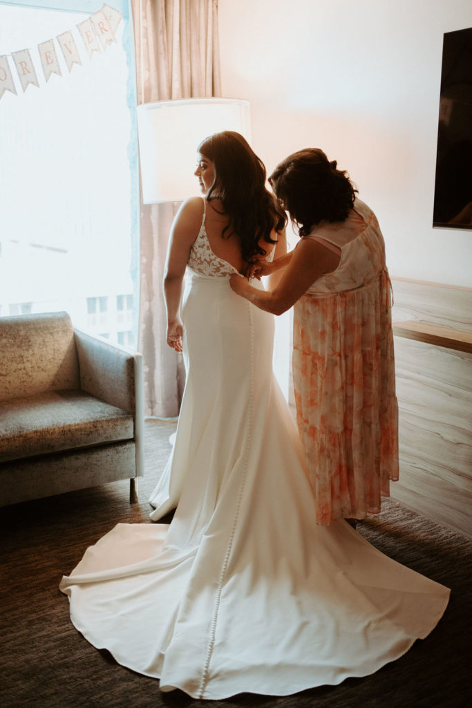 Mother helping bride in wedding dress 