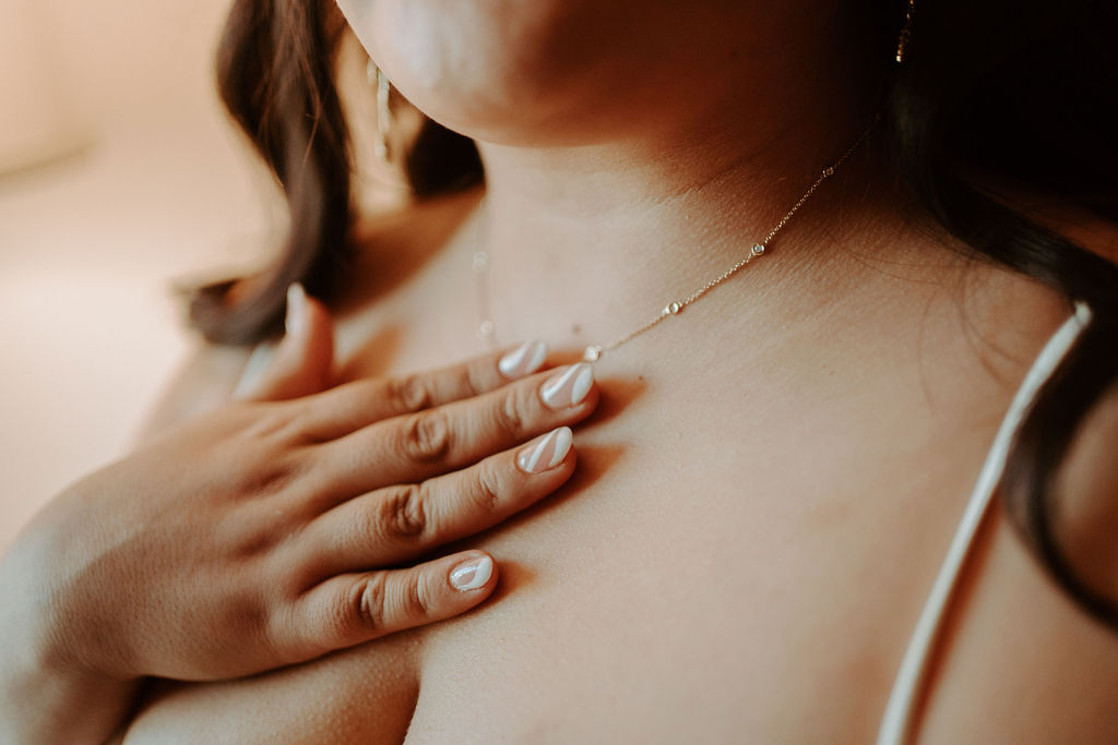 Bride with manicured nails touching her necklace 