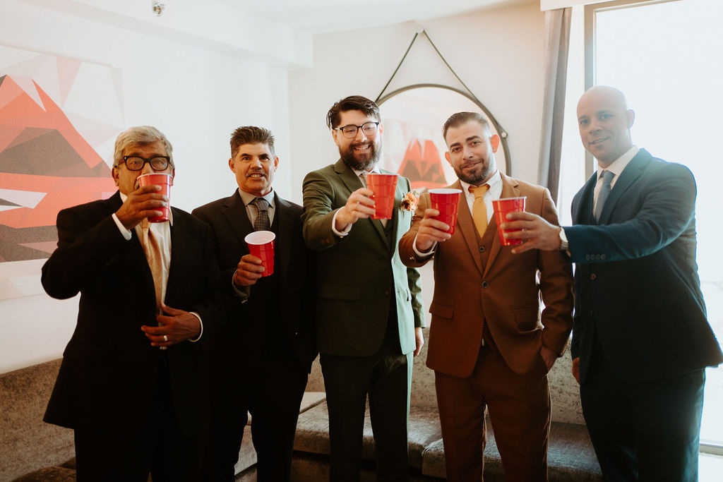 Groom celebrating with groomsmen while getting ready 