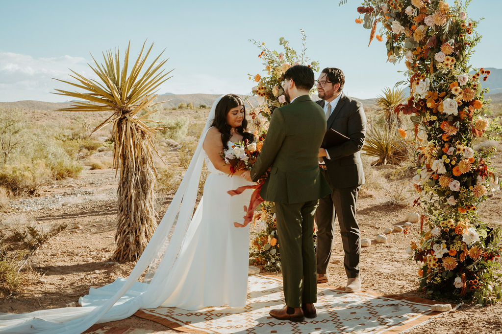 Couple getting married in Las Vegas desert with orange, blush, beige, terracotta climbing florals 
