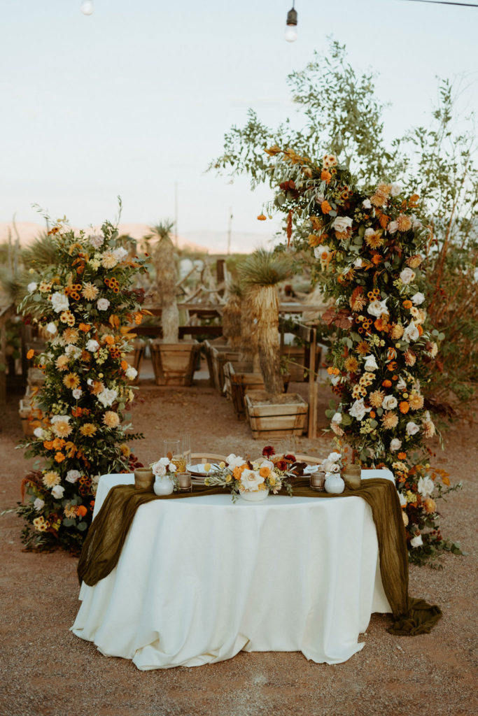 Fall inspired sweetheart table with climbing florals in the background 
