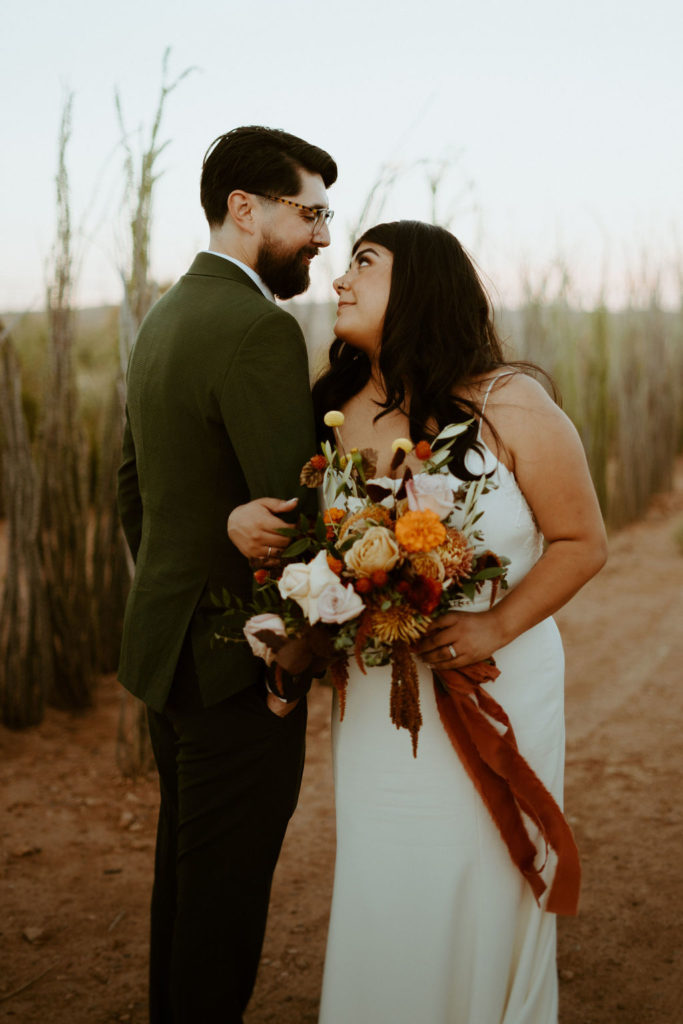 Newlyweds at Cactus Joes, Bride holding Terracotta, Orange, Blush and Beige Bouquet with greenery bouquet 