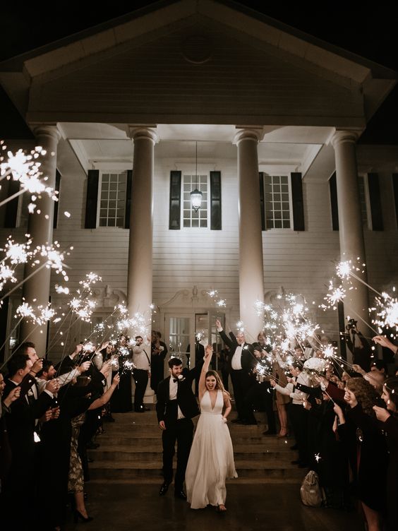 The newlyweds make their down the aisle of sparklers as guest cheer them on 
