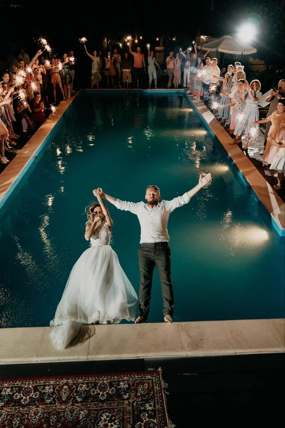 Newlyweds jump in the pool as guest cheer them on for their grand exit