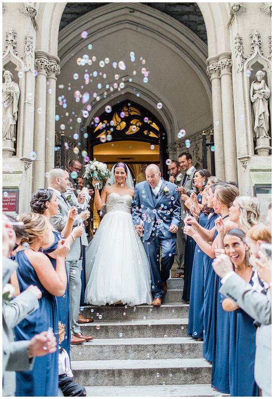 Grand exit ideas. The bride and groom make their way down the stairs of the church as the guest blow bubbles
