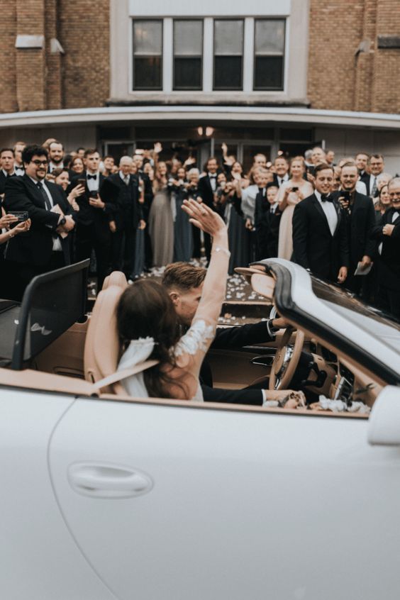 Grand exit ideas. Newlyweds drive off in a vintage car waving to guest leaving ceremony.
