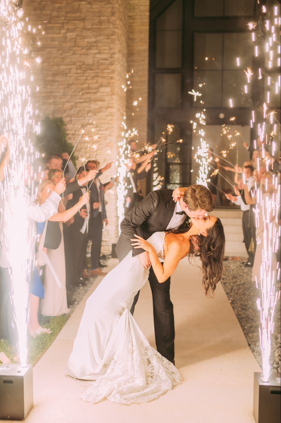 Grand exit ideas. Newlyweds stop in the middle of the cold sparklers to kiss 