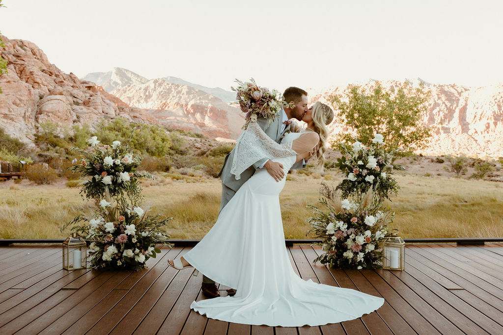 Red Rock Desert & Neon Vegas Lights. Newlyweds kissing at the altar on the boardwalk in calico basin at red rock canyon 