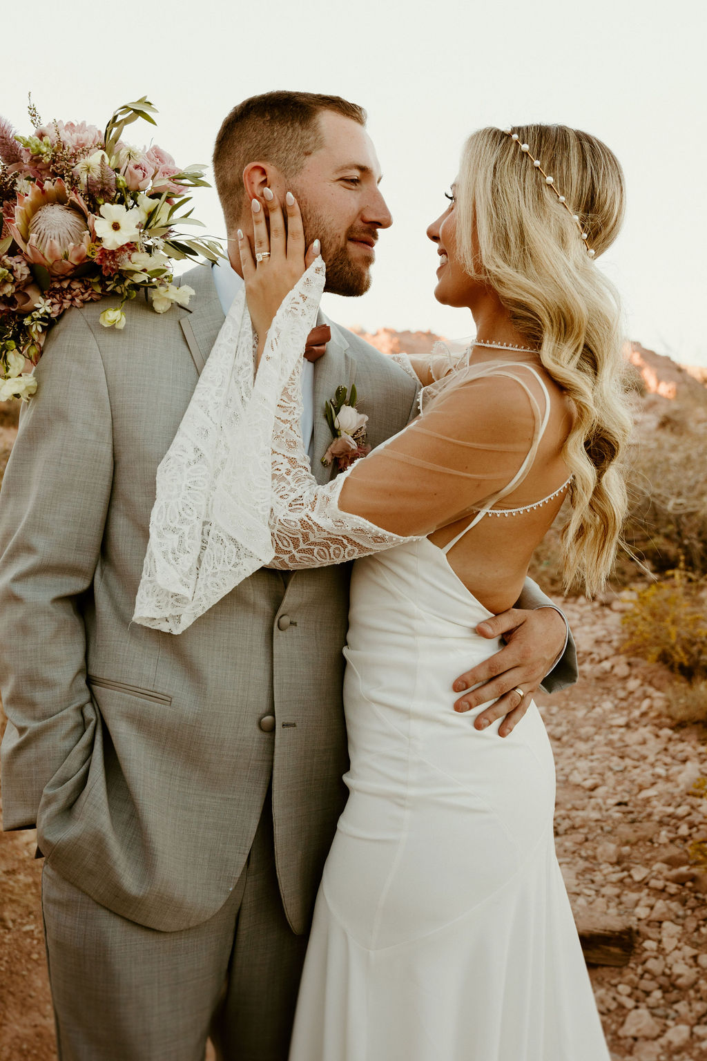 Red Rock Desert & Neon Vegas Lights. Bride holding the grooms face with her bouquet behind his head 
