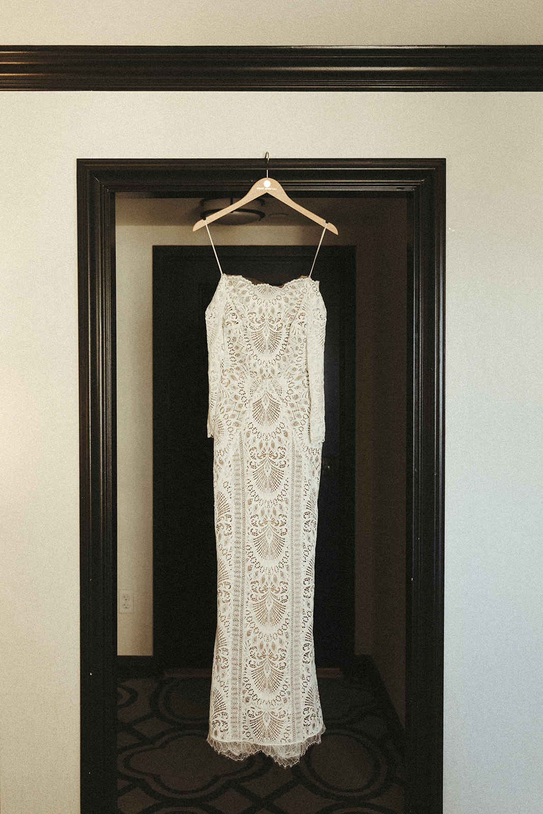 The brides lace silhouette wedding dress hanging in the doorway of the bridal suite 