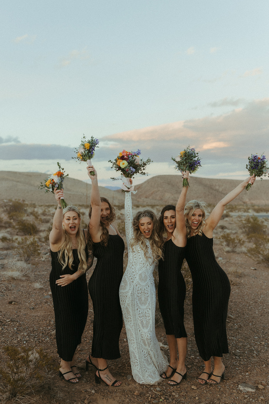 The bride poses with her bridesmaid all throwing their color bouquets in the air