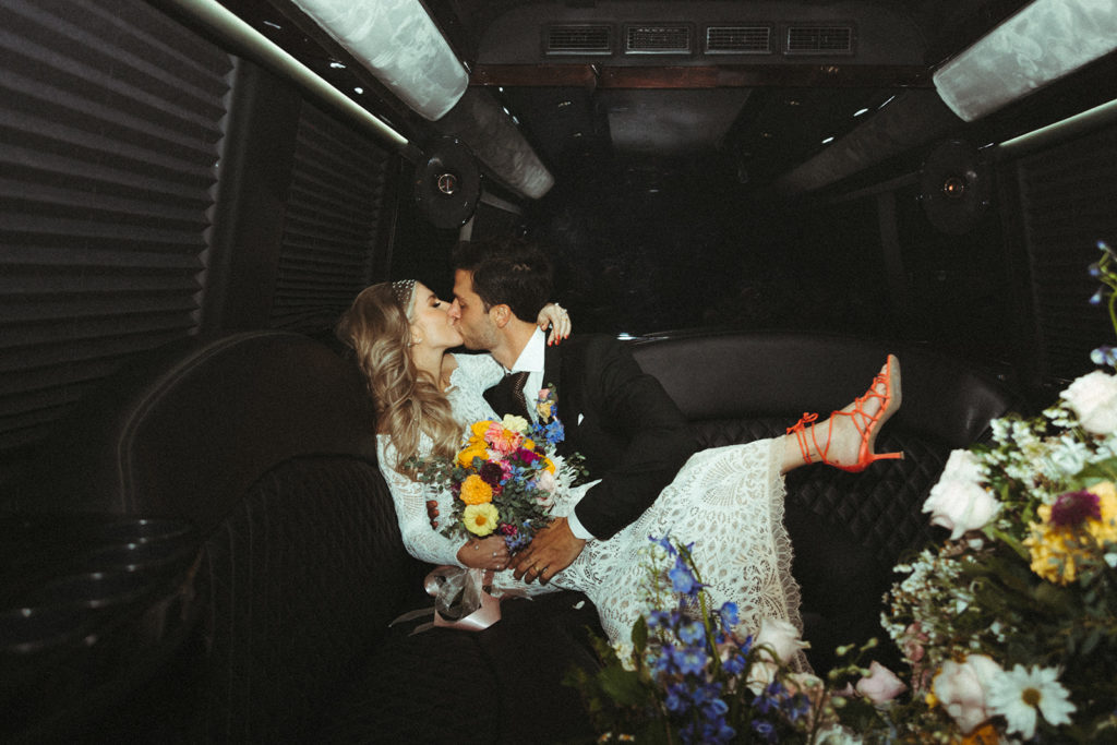 Retro & Colorful Micro-Wedding at the Doyle. Newlyweds kiss in the back of the party bus 