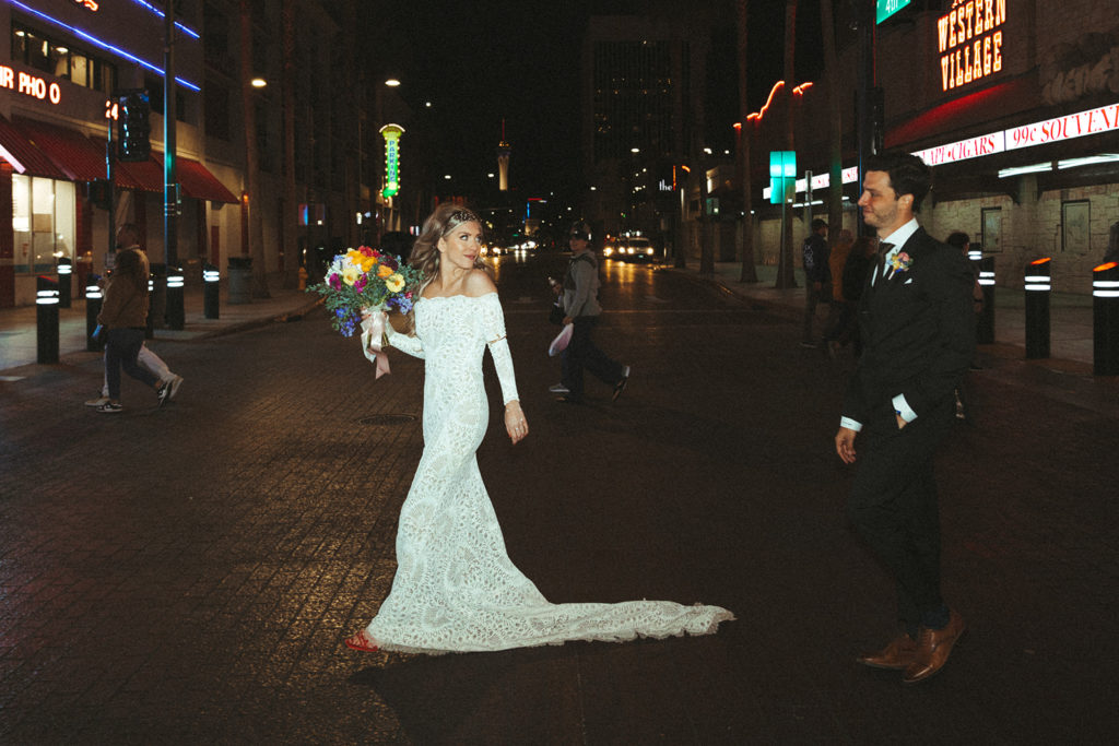 Bride walks ahead of the groom downtown and looks back at the groom 