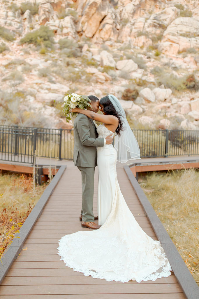 Newlyweds hugging after getting married for Calico Basin Red Springs Autumn Elopement  with natural rock backdrop