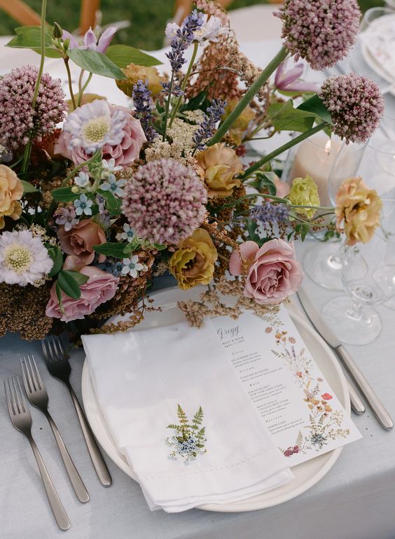 Natural and organic garden theme table scape with earthy muted colors in the wildflower centerpieces surrounded with candles and a custom garden theme menu card