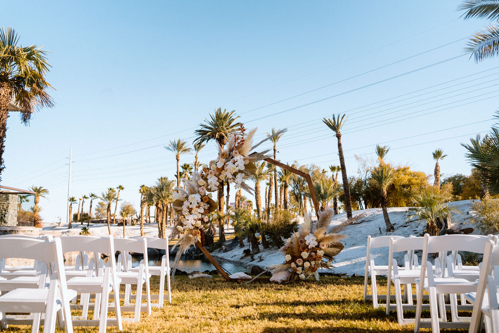 Ceremony chairs lined up to make an isle with the boho themed octagon wedding arch in the center. 
