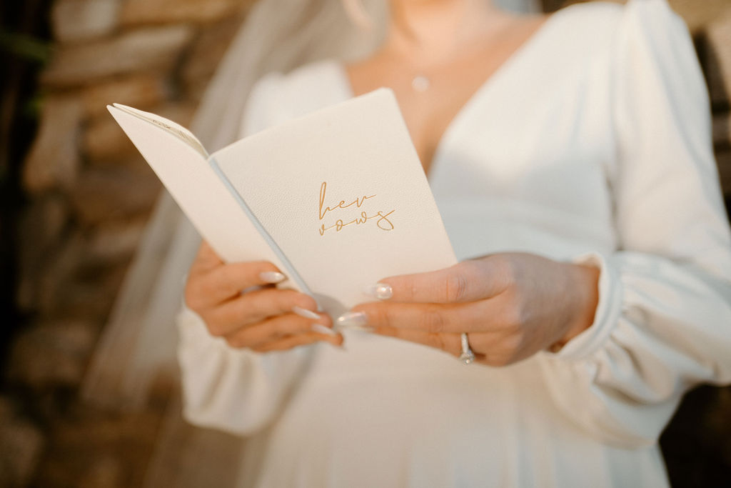Close up of the brides vow booklet white with gold lettering. 