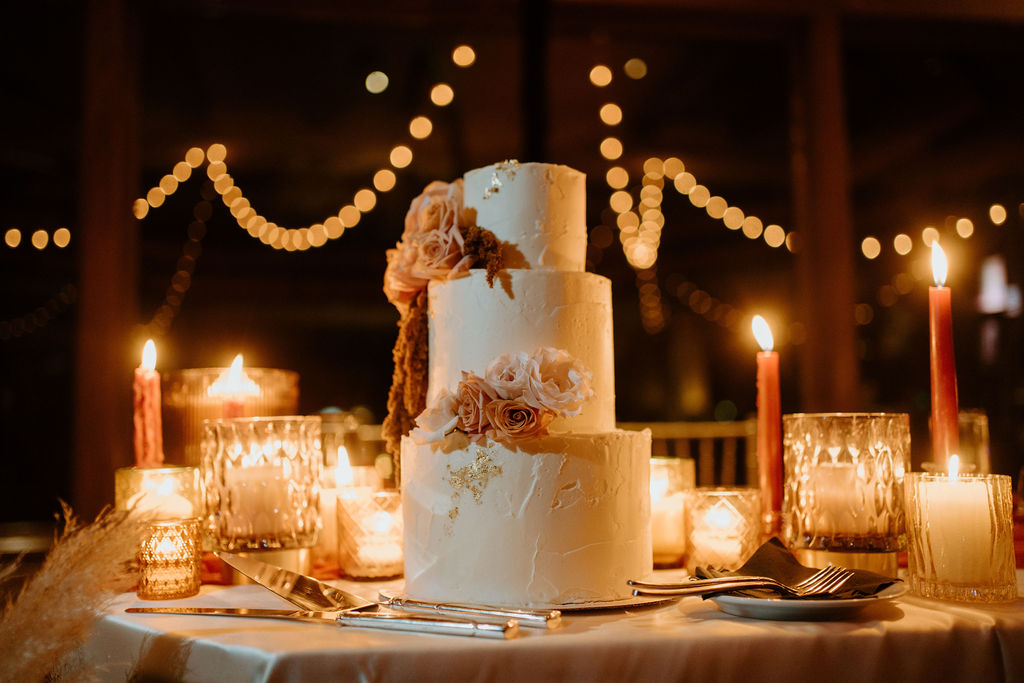Beautiful three tiered wedding cake with elegant candles twinkling around it. 
