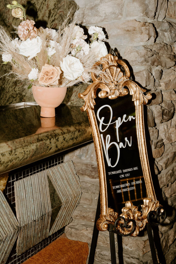 Open bar menu written on a beautiful mirror. A boho floral center piece arranged next to it. 