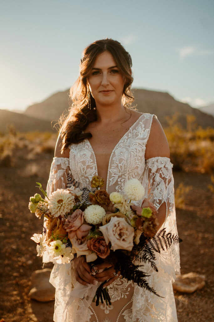Close up of the beautiful bride. Mountains in the background and holding her dusty pink, white, and toffee colored bouquet. 