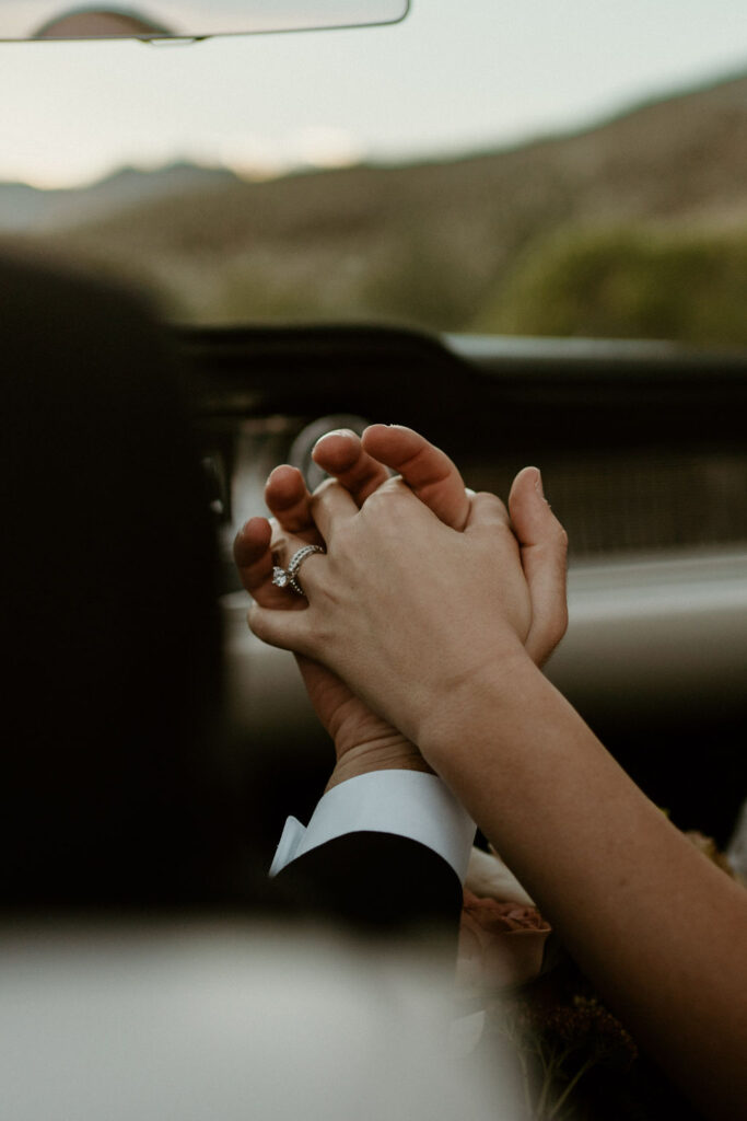 Close up of couple holding hands inside the car. 