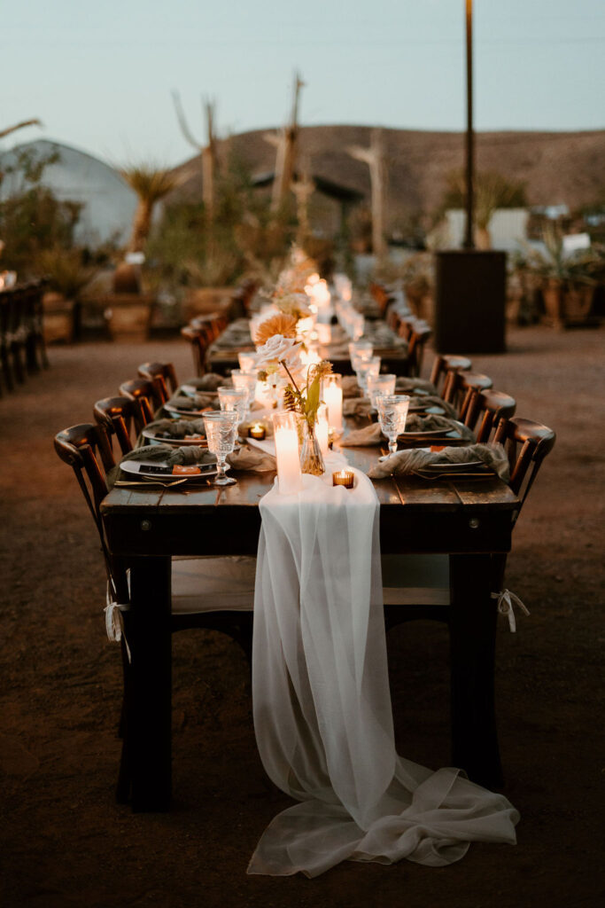 Wide shot of table decorations with candles lit up. A dark modern Boho styled decor. 