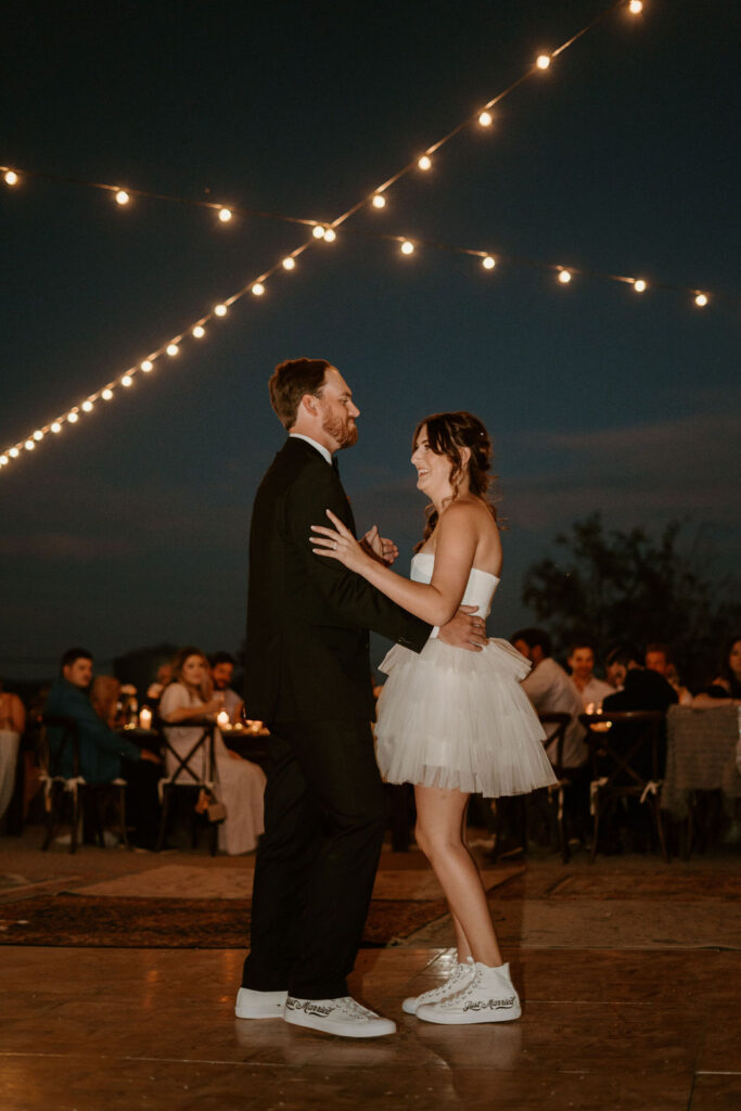 Bride and groom having their first dance under bistro lights on the dance floor. 