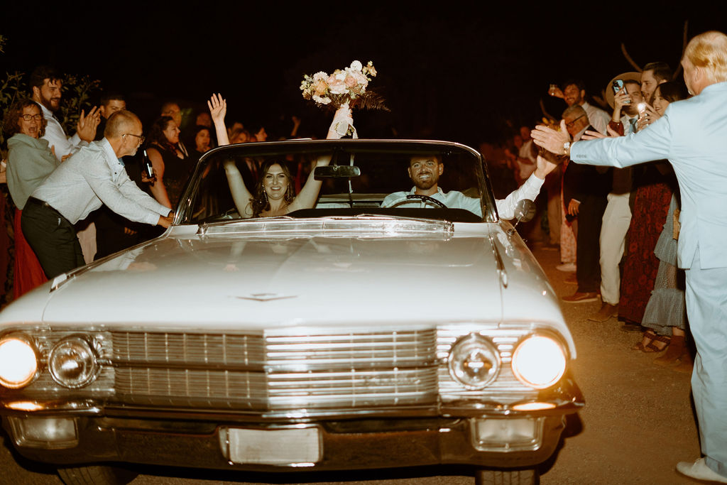 Candles, Pampas, & Romance at Cactus Joe's bride and groom hop in the old school Cadillac to leave their wedding. 