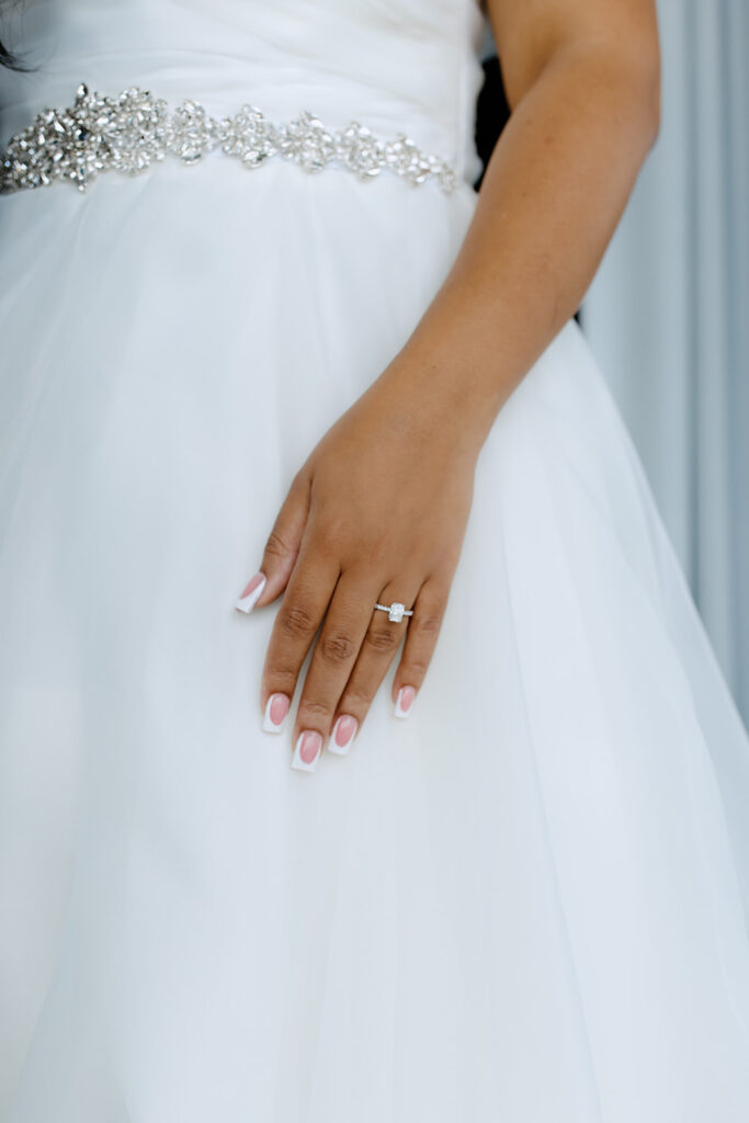 Close up photo of the detailing of the brides dress and her ring 