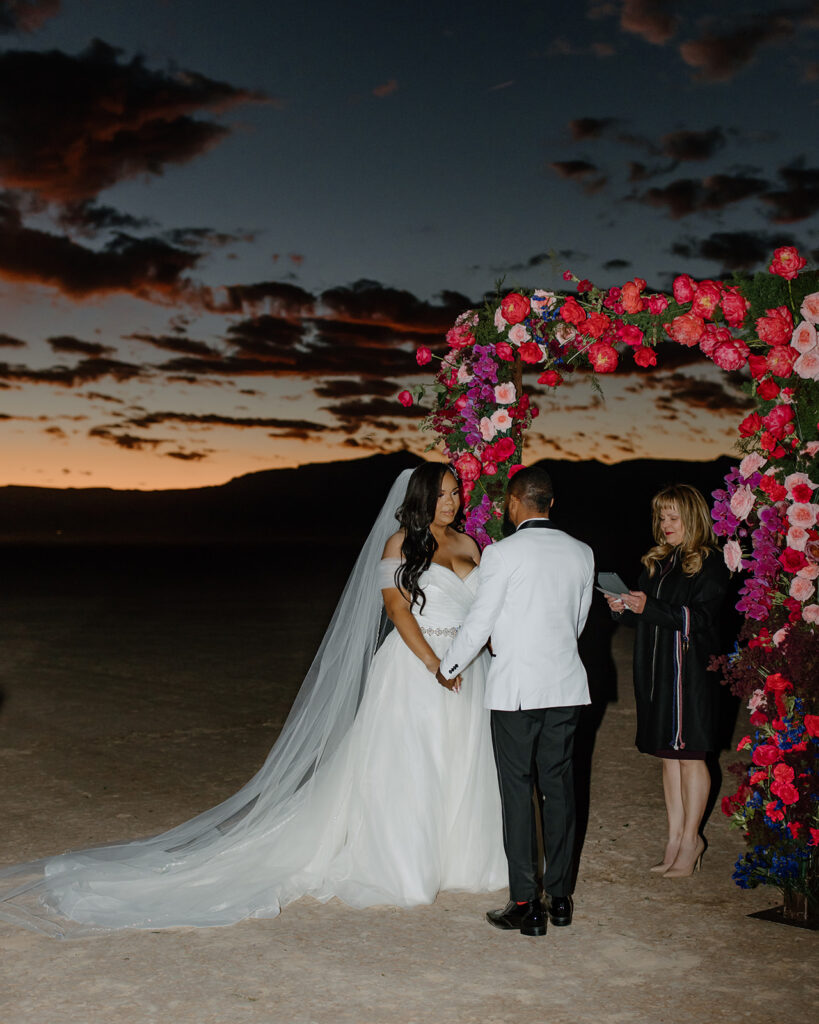Colorful & Romantic Elopement on the Dry Lake. Bride and groom holding hands at the altar 