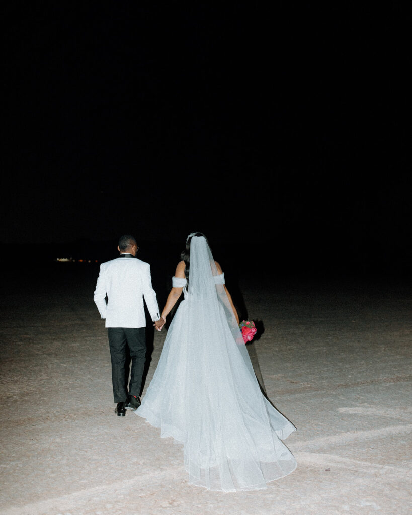 Newlyweds walking into the vast expense of the desert 