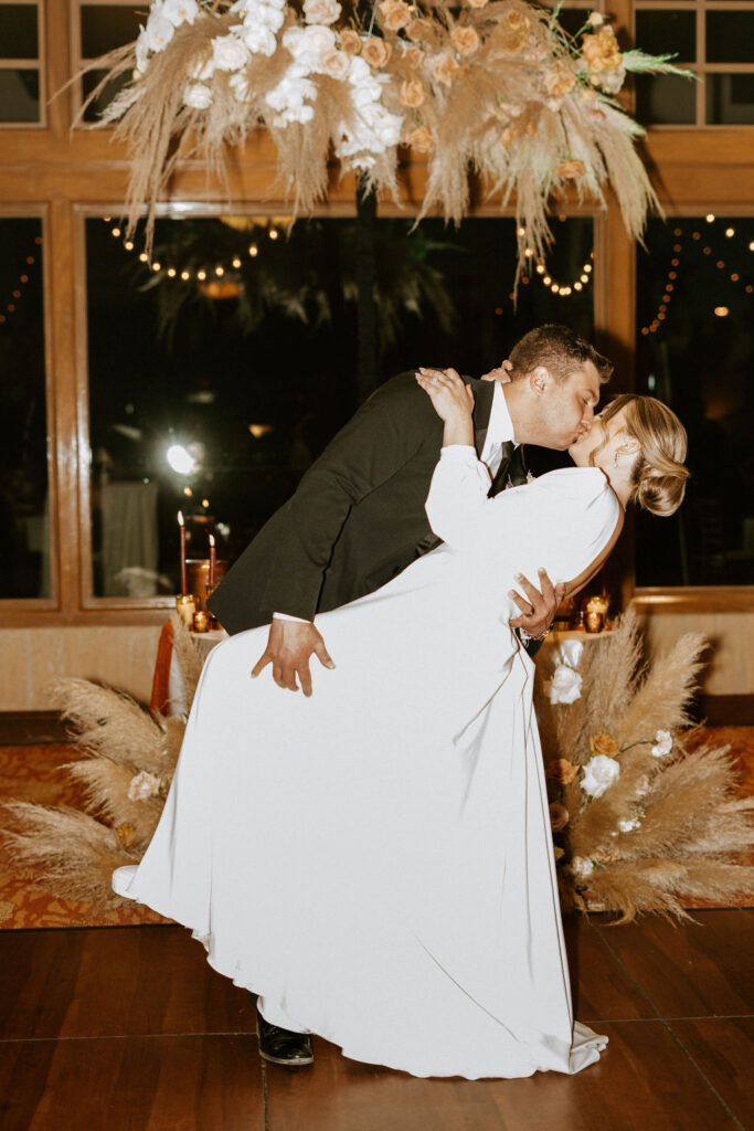 Groom dips his bride in a kiss during their dance. 