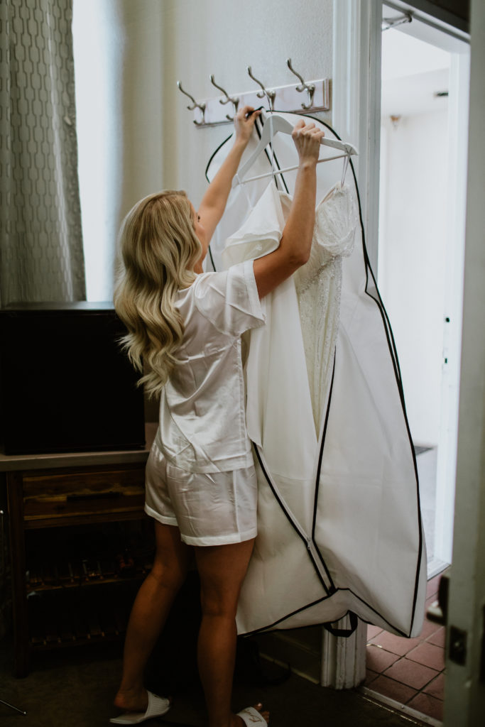 How to Travel With a Wedding Dress. Bride unzipping her garment bag to get her wedding dress out.
