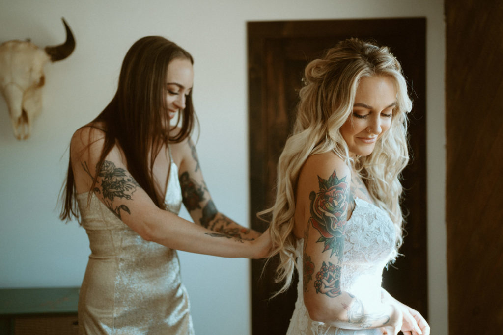 How to Travel With a Wedding Dress. Maid of honor helping the bride get into her wedding dress 