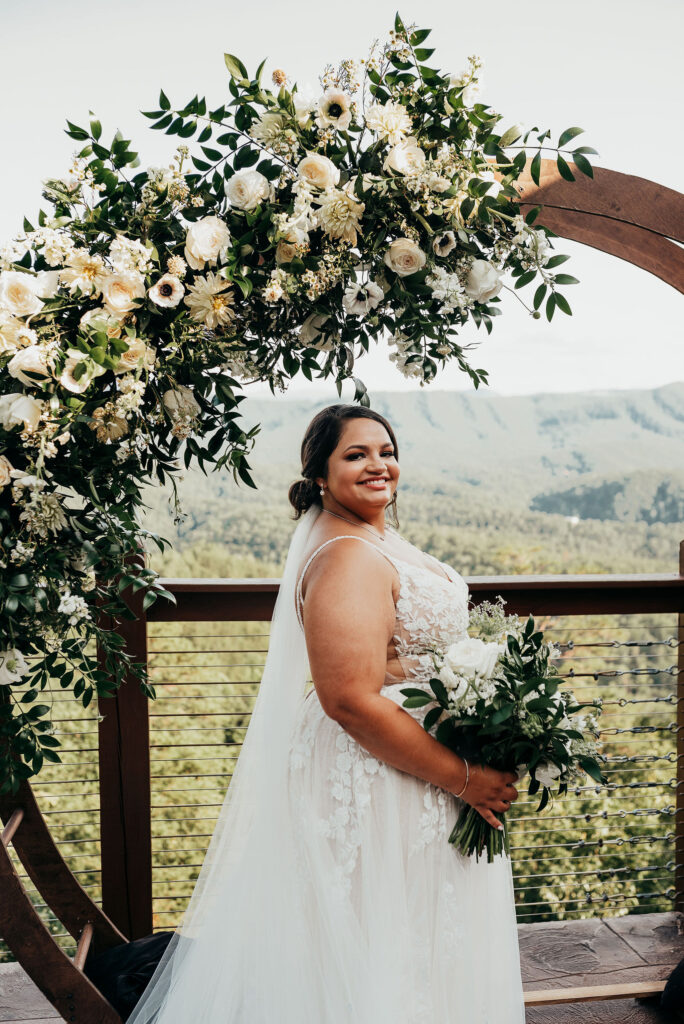 Bride standing in front of the circular arch smiling 