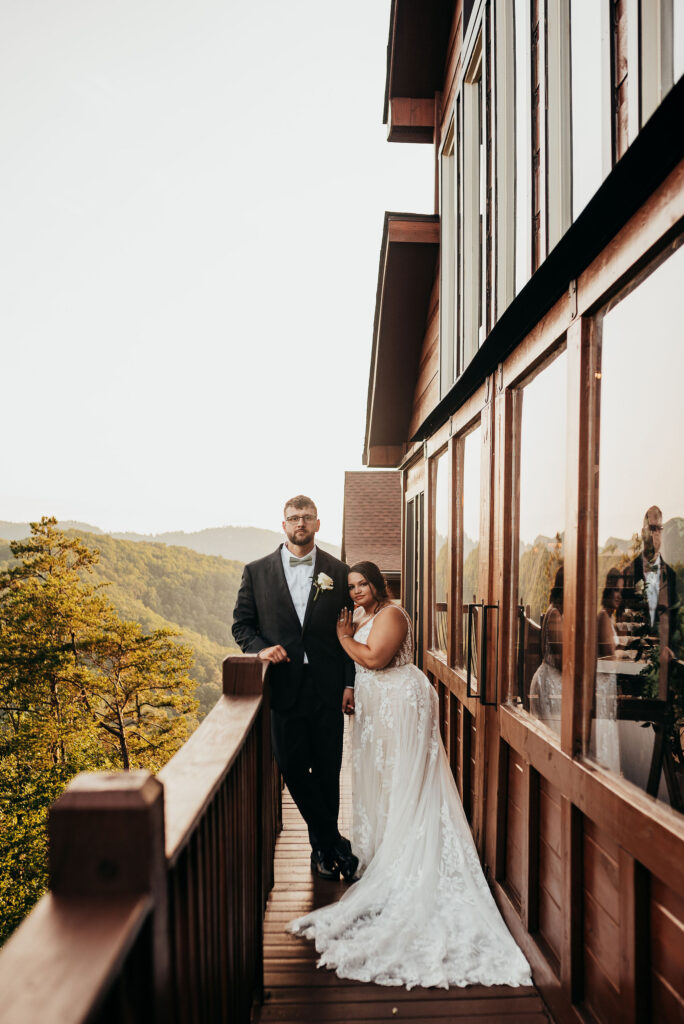Newlyweds standing on the patio of the grand hall in the middle of the smokey mountains 