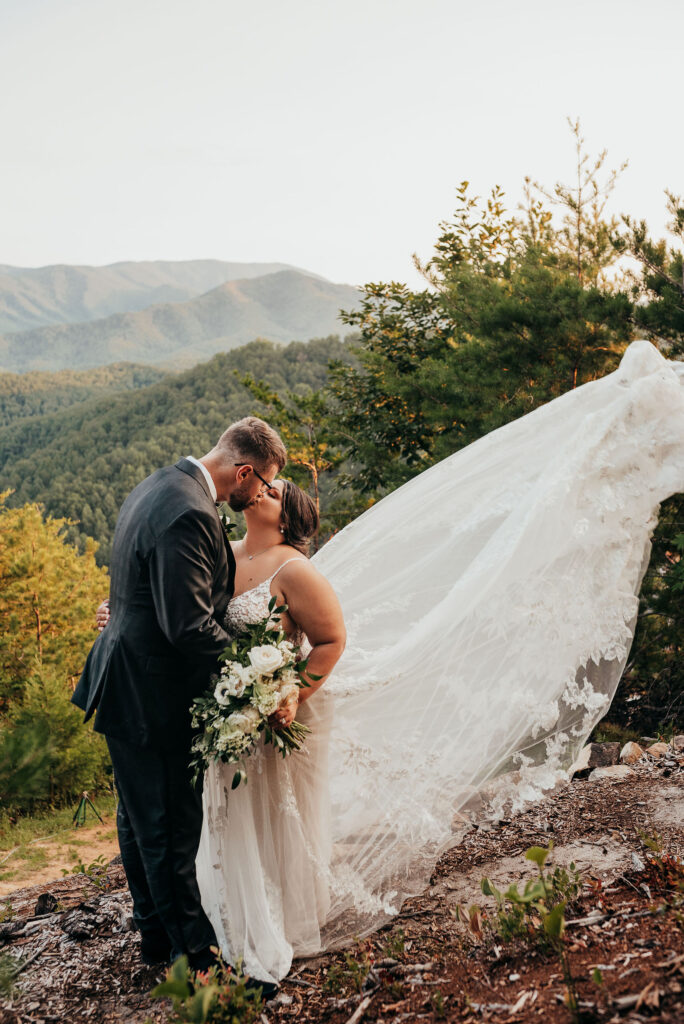 Rolling Hills and Tennessee Whiskey. Newlyweds kissing in the mountains as her dress flows in the air 