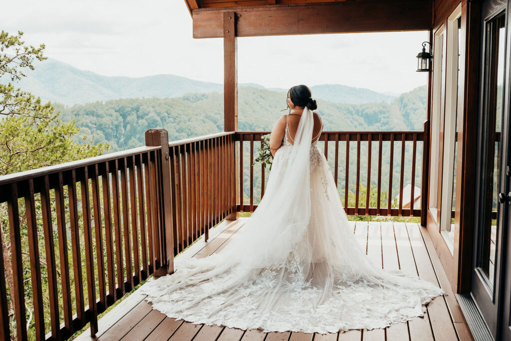 Rolling Hills and Tennessee Whiskey. Bride standing outside on the patio of the bridal suite facing out to the great smokey mountains in her gorgeous lace detailed wedding dress  