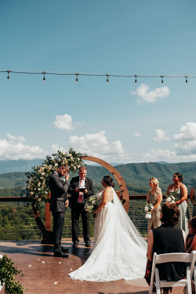 Rolling Hills and Tennessee Whiskey. Bride and groom standing in front of the wooden circular arch draped in florals 