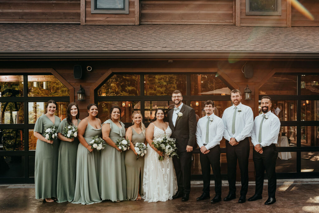 Bridesmaid and groomsmen stand on each side of the bride and groom as they take group photos