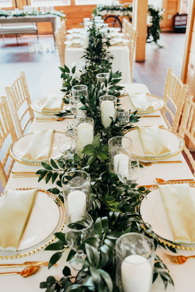 Table setting. Lush greenery runner with candles placed sporadically alongside 