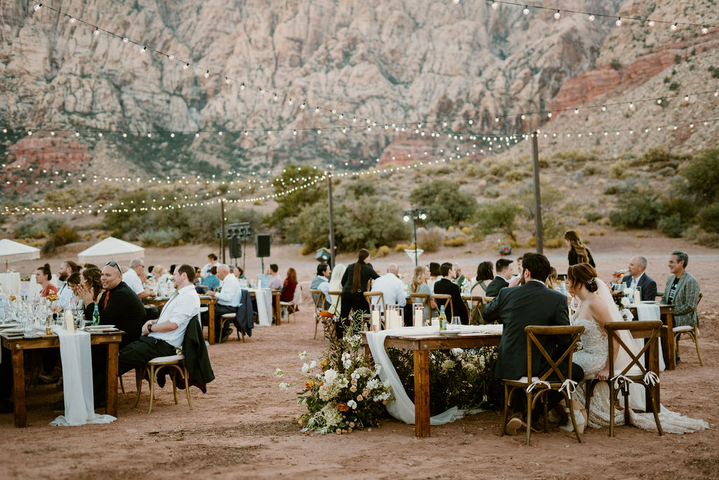 Timeless Red Rock Canyon Wedding side view close up of the backside of the his and her table. Bride and groom observe their guests and enjoy their dinner. 