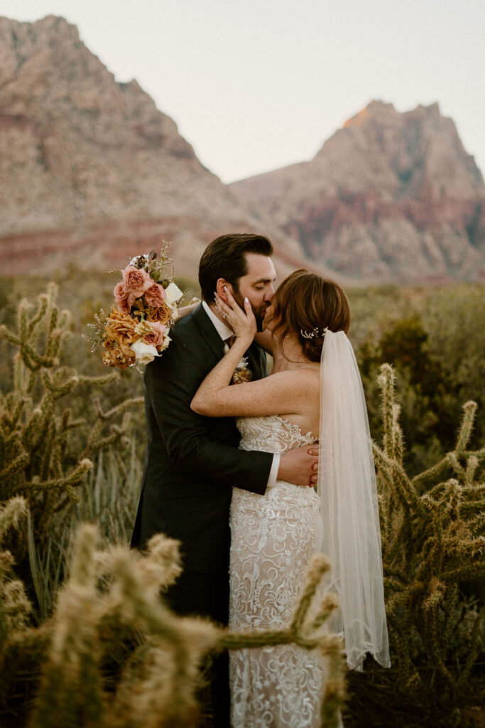 Timeless Red Rock Canyon Wedding bride and groom kissing as groom holds her hips and she caresses his face. 
