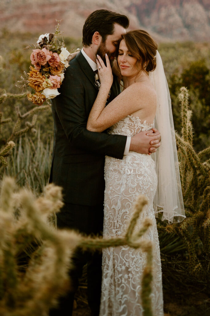 Cactus is out of focus in the camera shot as the bride caresses her grooms face as he pulls her close. 