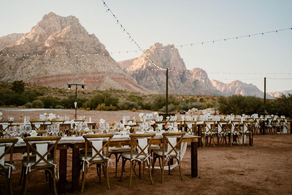 Timeless Red Rock Canyon Wedding dinner and reception dinner set up. Mountains in the background and hanging lights. 